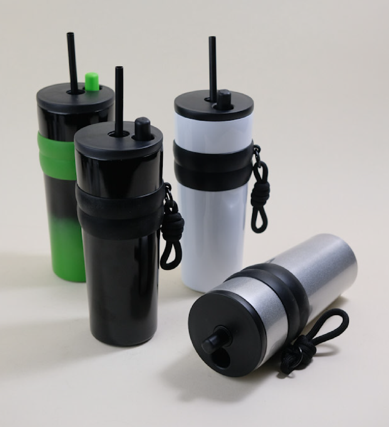 An array of stainless steel straw tumblers in assorted colors including black, green, white, and silver, each featuring a BPA-free plastic straw and a convenient rubber grip. These tumblers are designed for easy customization and portability, suitable for both hot and cold beverages.