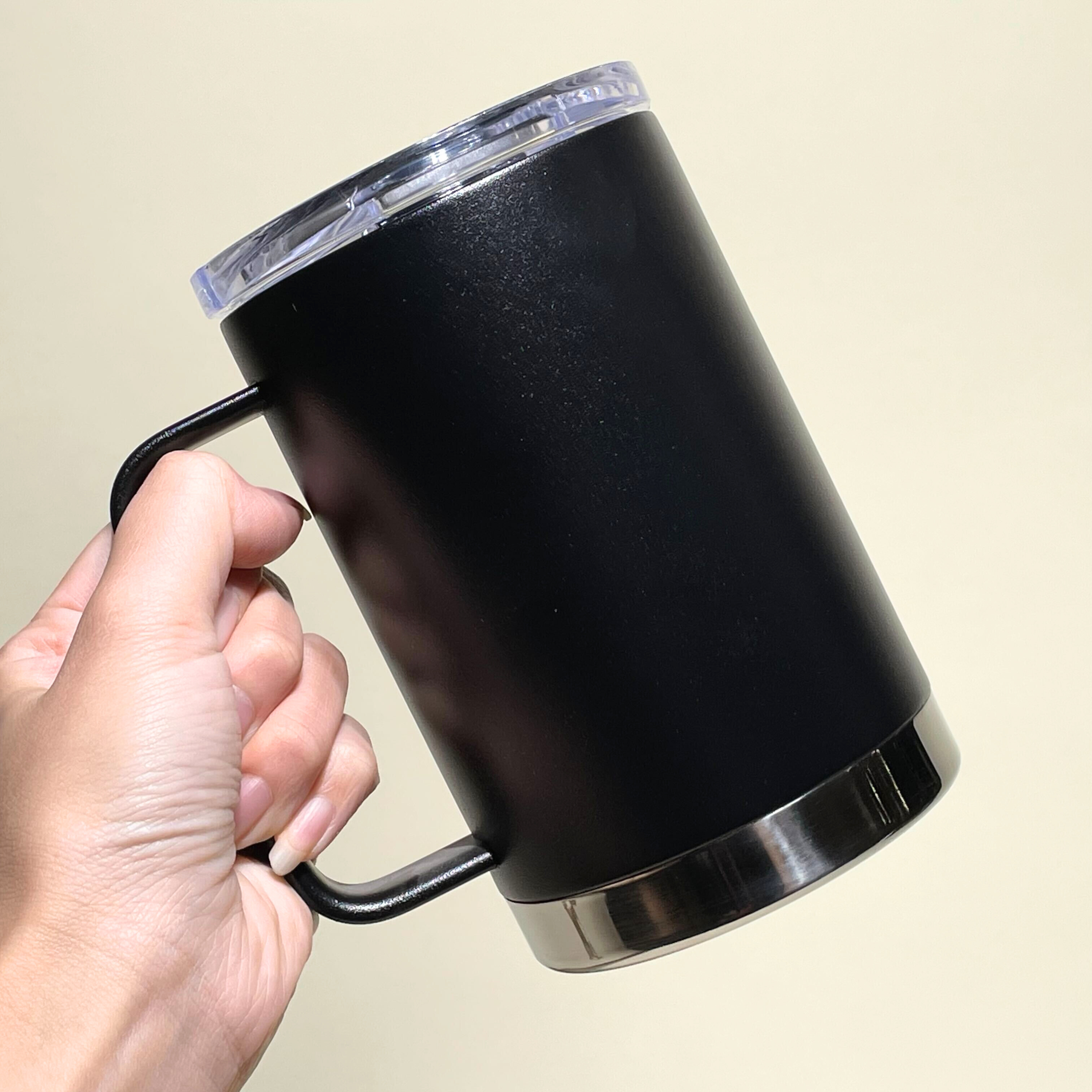 LAMOSE Hudson Pro Max 24 oz black stainless steel insulated mug, held in hand. Features a clear lid, ergonomic handle, and polished steel base.