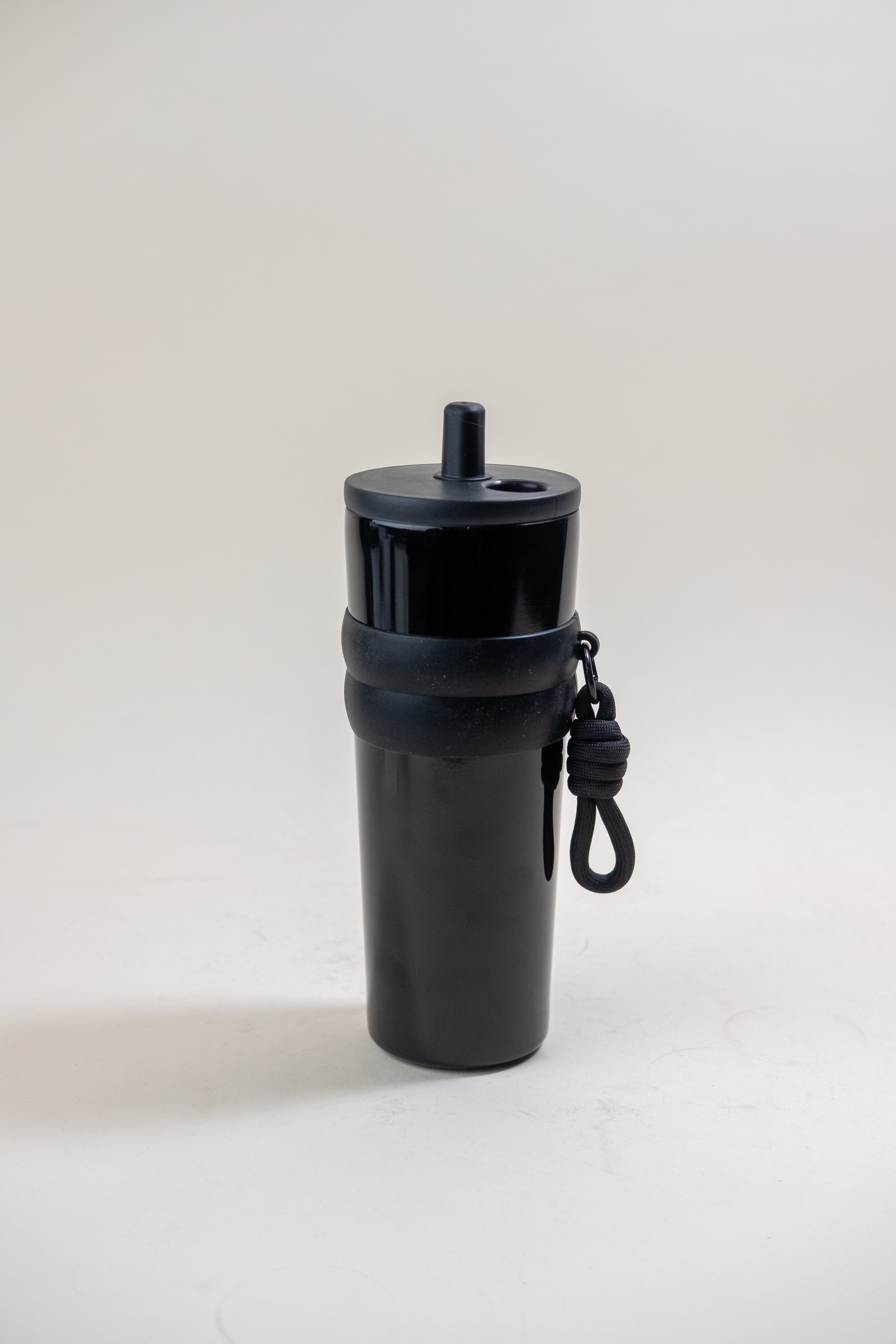 black stainless steel straw tumbler featuring a BPA-free plastic straw and black rubber grip bands, complete with a convenient carrying rope, perfect for on-the-go hydration.