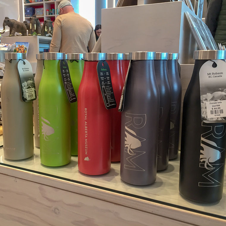 LAMOSE insulated bottles: beige, green, red, grey, black. Custom branded for RAM & Mt. Robson, displayed in a store.