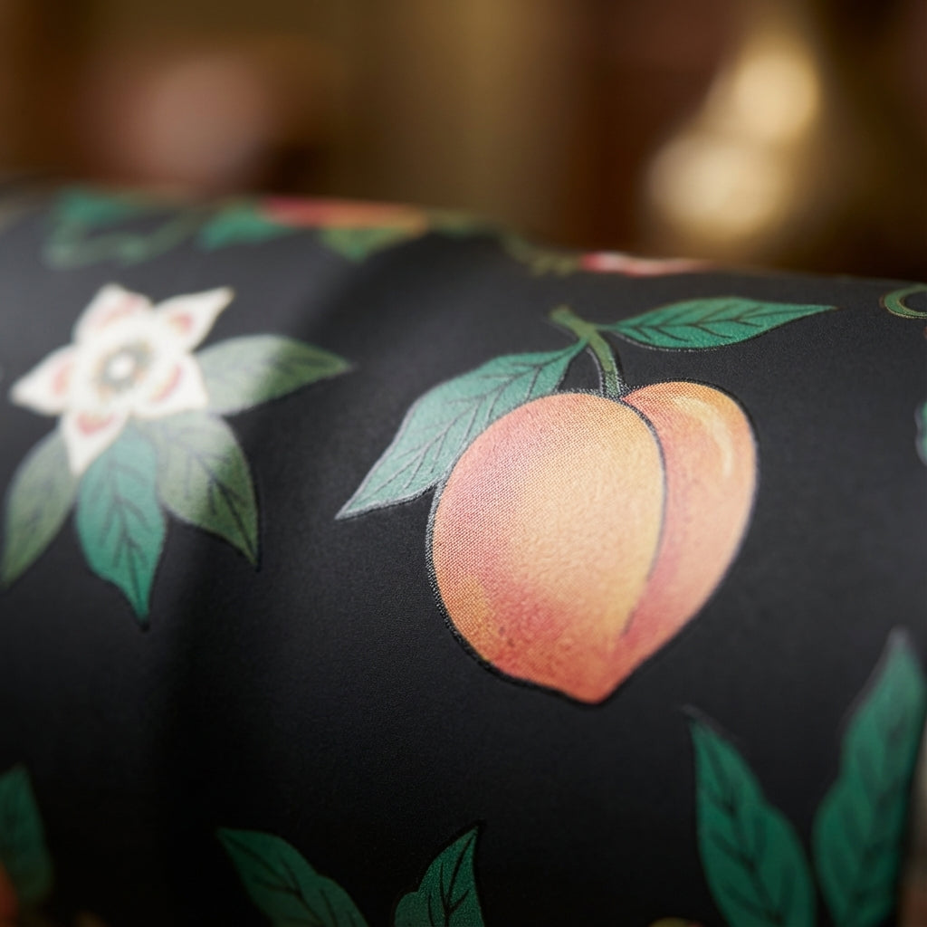 Detail shot - LAMOSE Bow 16 oz insulated tumbler featuring a dark botanical pattern with peaches, persimmons, and white flowers on a black soft-touch background.