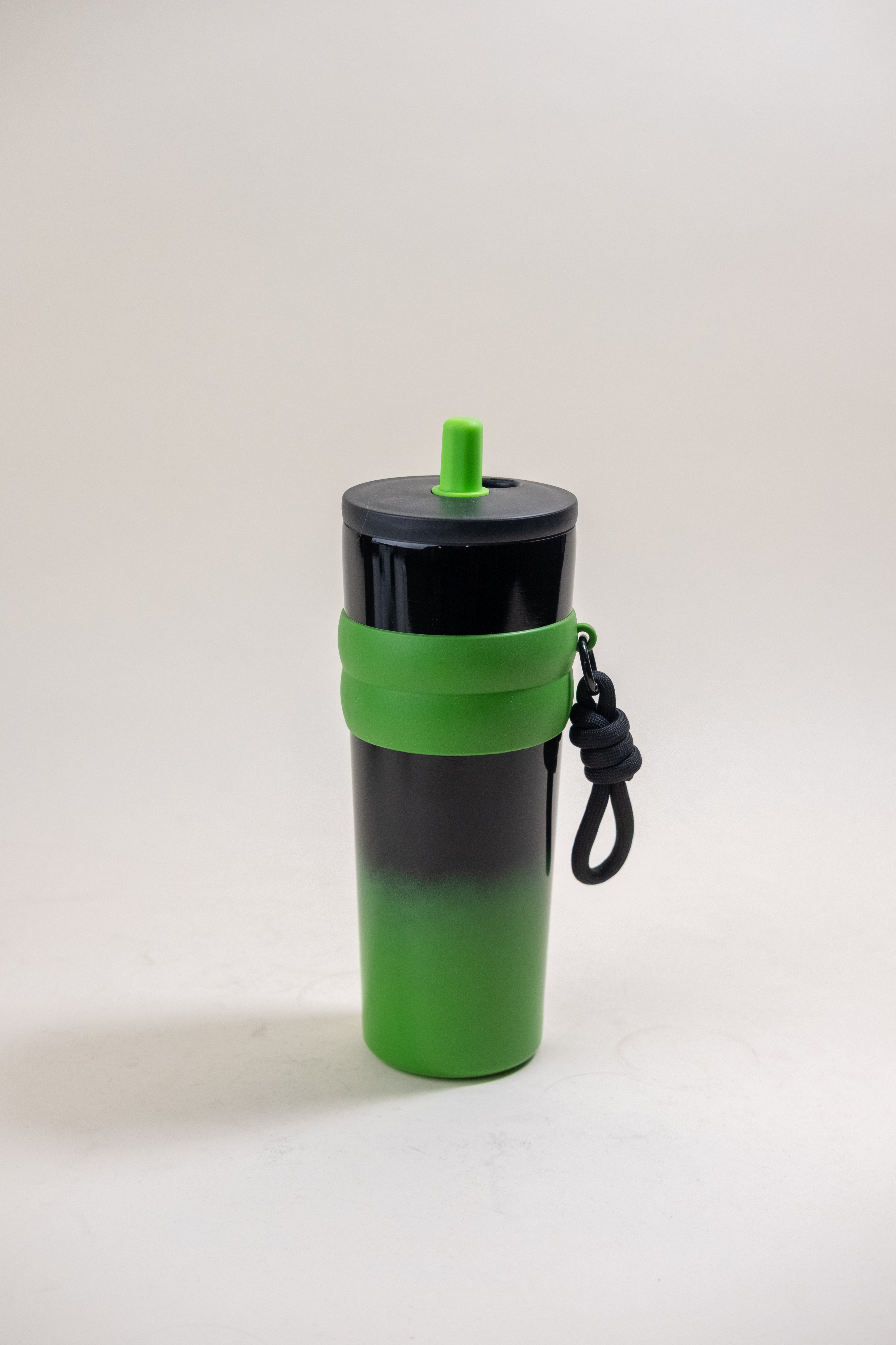 Stylish two-toned straw tumbler in black and green with a matching green BPA-free plastic straw and a black rubber grip for enhanced handling, complete with a portable rope for easy transport.