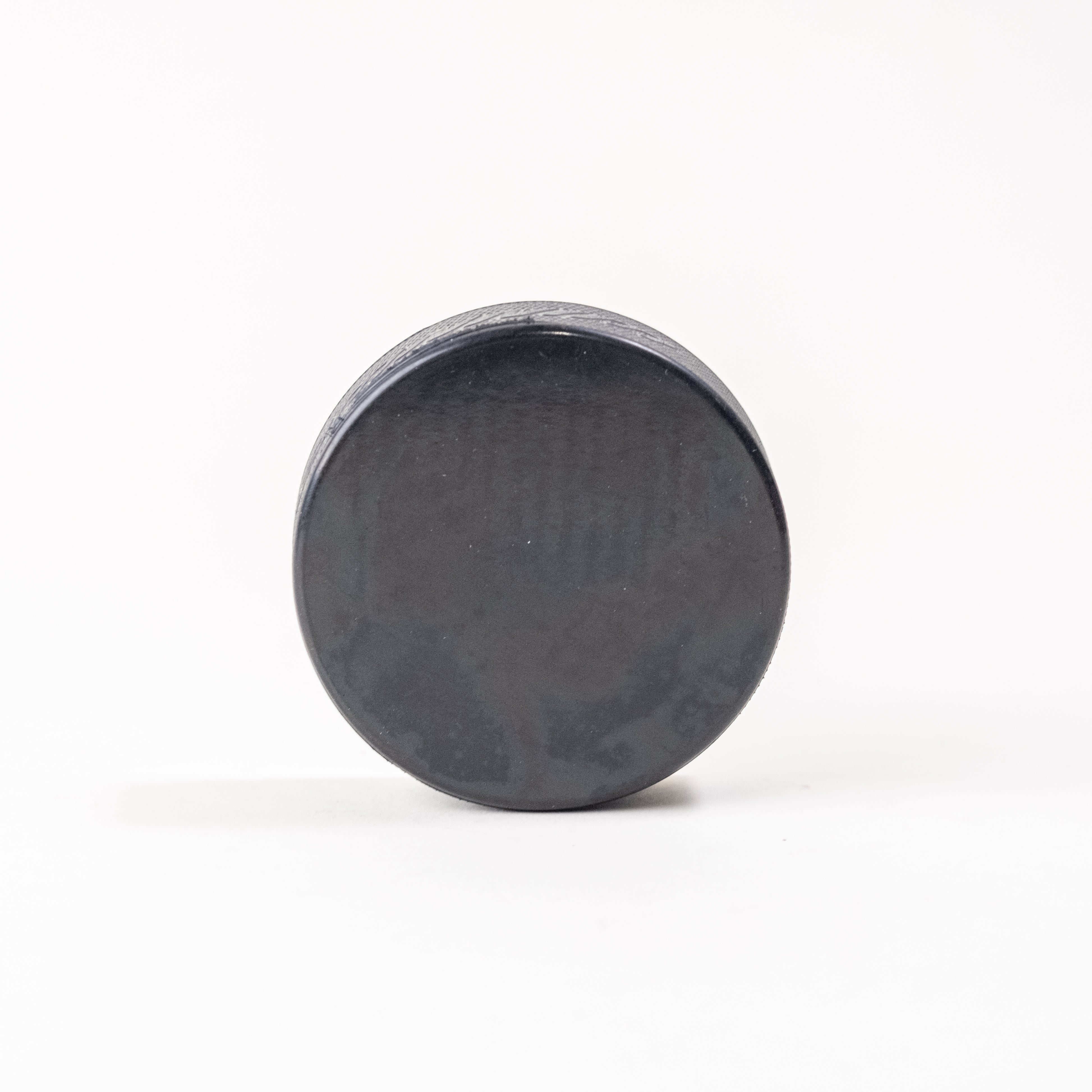 Black hockey puck standing upright on a white background. Official-size durable puck, ideal for gameplay, training, and custom engraving.