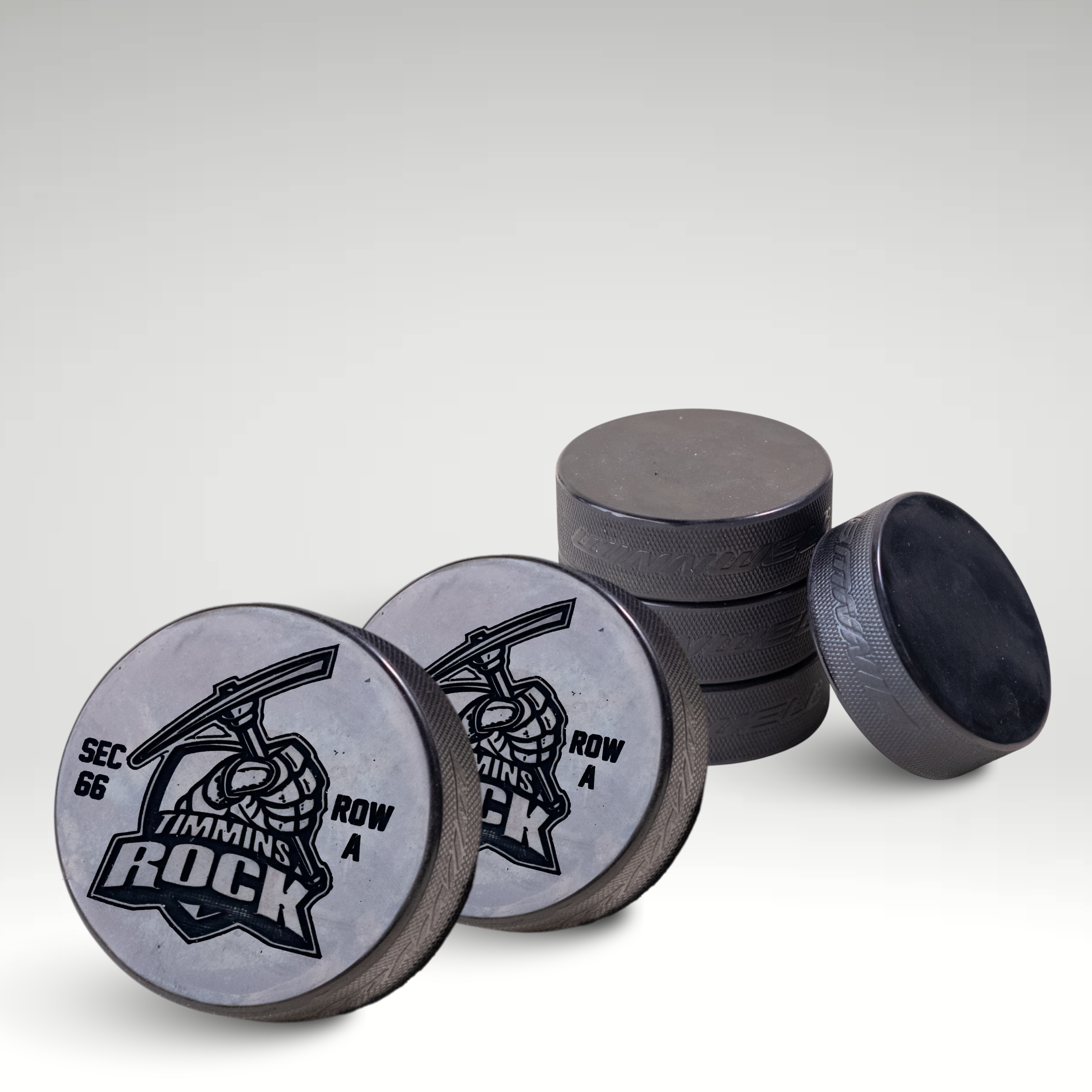 Custom engraved Timmins Rock hockey pucks with team logo and section row details.