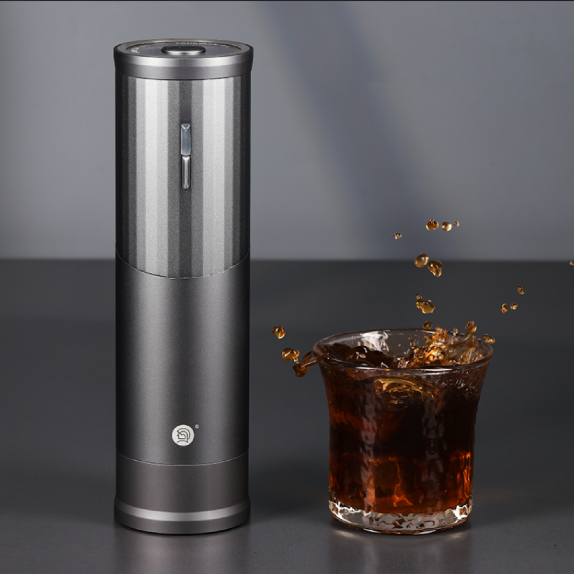 zeroHero RUI Portable Electric Coffee Grinder in grey, displayed next to a glass of freshly brewed coffee with dynamic splash effect, highlighting precision grinding for rich coffee flavors. #color_silver