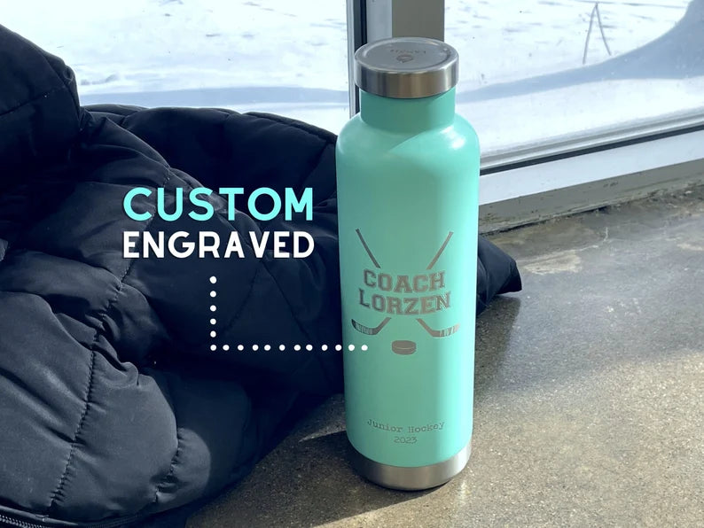 LAMOSE Moraine 27 oz light teal stainless steel bottle, custom engraved for 'COACH LORZEN' with hockey sticks and puck, upright.