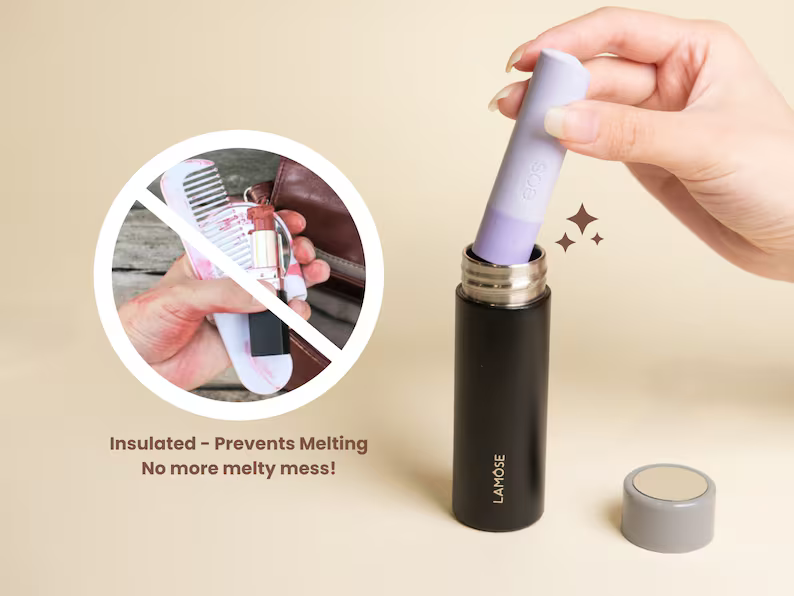 LAMOSE Maligne 1 oz insulated black onyx case, hand inserting a purple lip balm. Illustrates no more melted lipstick mess. Metal bottle, beige background.