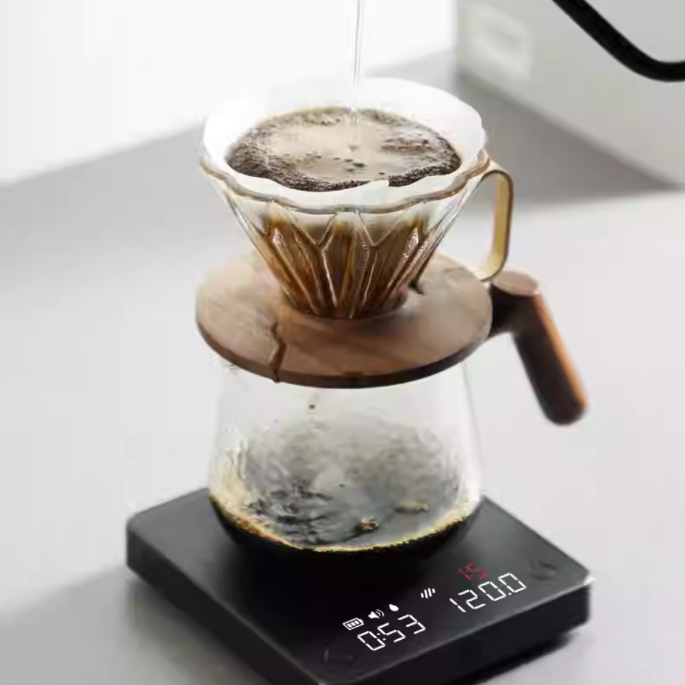 Pour-over coffee brewing with a glass dripper, wooden-handled server, and a digital coffee scale with a built-in timer and weight display for precision brewing. #color_black