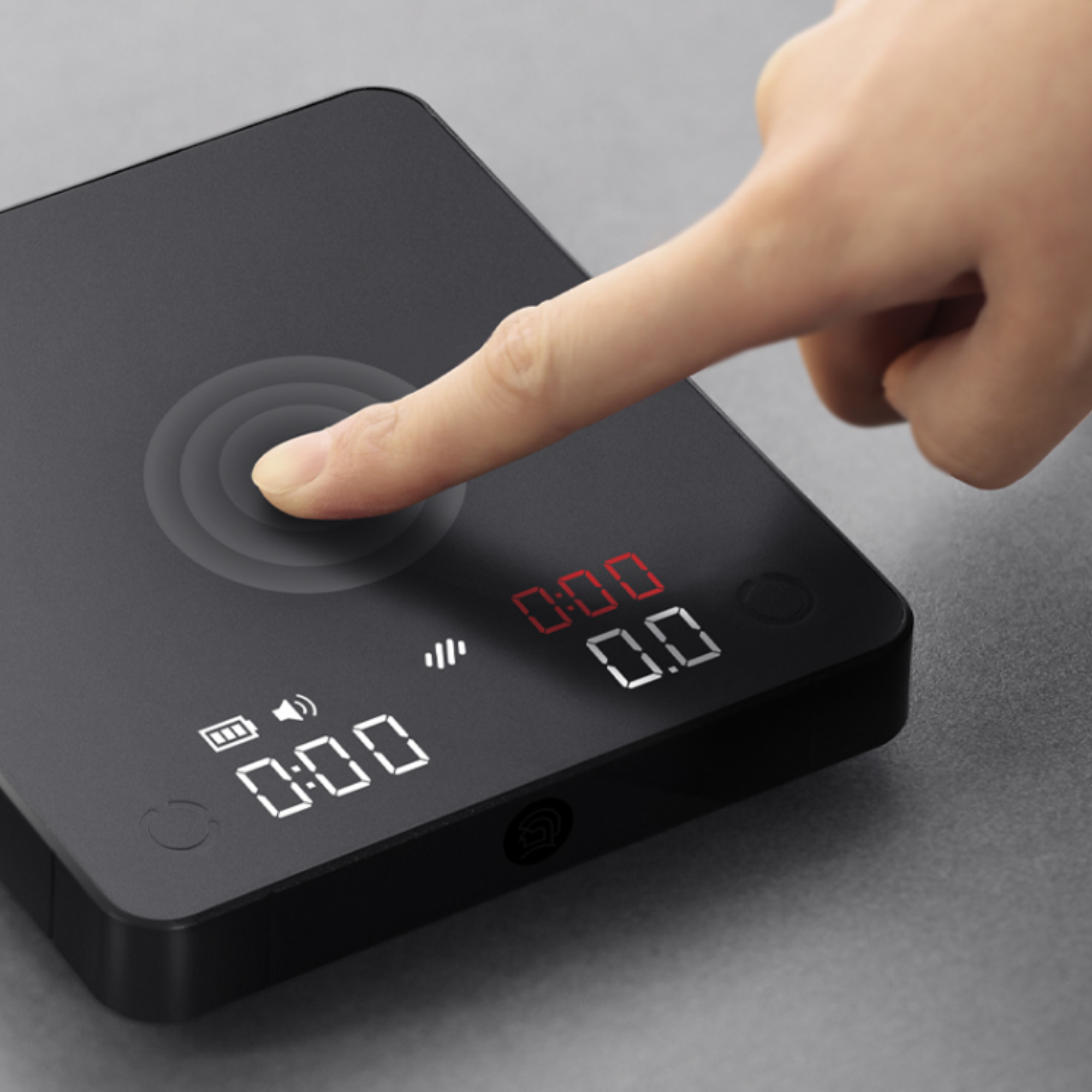 Close-up of a finger touching a black digital coffee scale with an LED display, featuring a responsive touch control for precision weighing and timer functions. #color_black