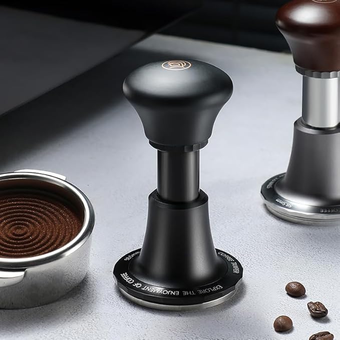 zeroHero 58mm calibrated espresso tamper in black, designed for precision coffee tamping with 30lbs pressure control, shown next to a portafilter with evenly compressed coffee grounds. #color_black