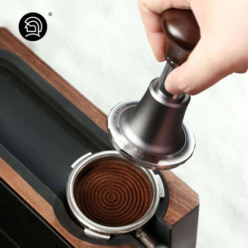 Barista using the zeroHero 58mm calibrated espresso tamper with a walnut handle and precision spiral base, ensuring even coffee ground compression for optimal espresso extraction. #color_mahogany