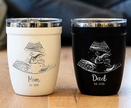 Personalized ultrasound engraved drinkware, showcasing black and white mugs and tumblers with custom engravings of ultrasound images and heartfelt messages as a tribute to expectant parents.