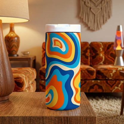 Grouse 12 oz insulated tumbler featuring a retro 1970s psychedelic swirl pattern in orange, blue, and cream on a teak table.
