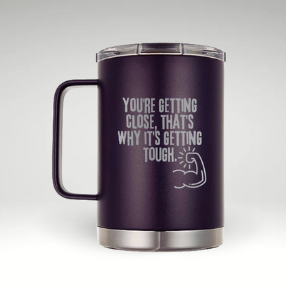 Motivation Muscle Insulated Mug Design Insulated mug with bold typography and muscular arm illustration featuring the quote YOU'RE GETTING CLOSE, THAT'S WHY IT'S GETTING TOUGH. 