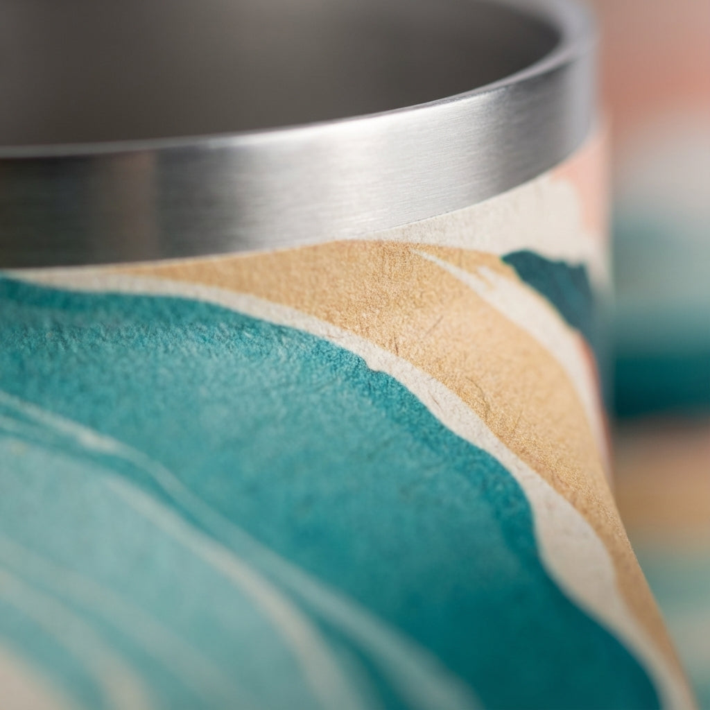 Detail shot - LAMOSE Bow 16oz tumbler featuring a peach and teal mountain landscape design sitting on a wooden surface with a peach lid and blue straw