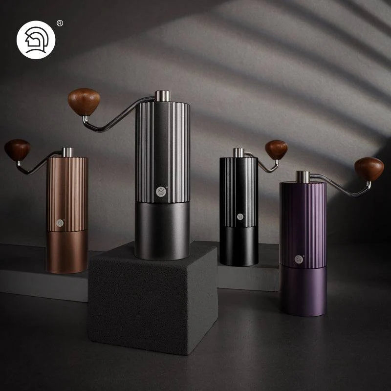 Premium manual coffee grinders in black, bronze, purple, and matte black with a sleek ribbed design, wooden handle, and precision burr grinder for consistent coffee grounds
