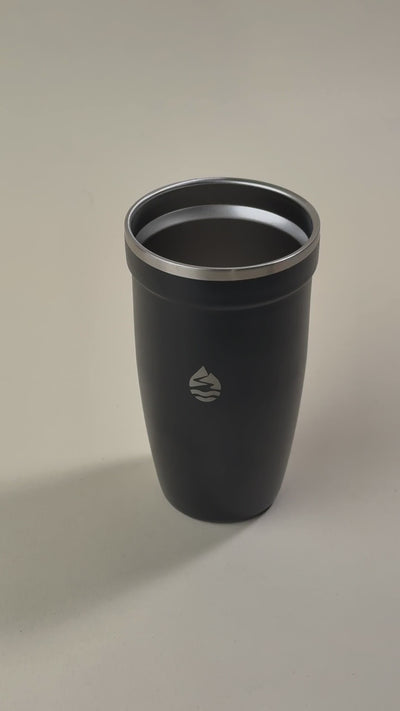 Hand holding a transparent spill-proof lid over a black insulated tumbler, showcasing its secure and leak-resistant design.